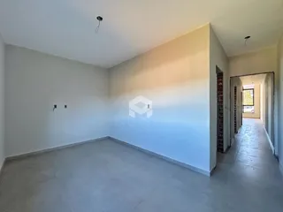 Vista interna de uma sala com paredes brancas e piso cinza.