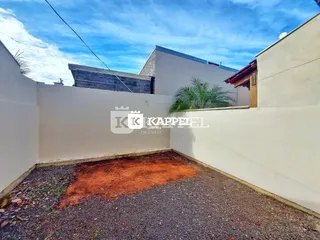 Foto de uma área externa com piso de cascalho e muro branco.