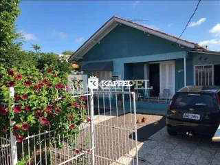 Fachada de uma casa azul-turquesa em Lajeado, Brasil, com cerca e vegetação na frente.