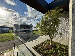 Vista da fachada de uma residência moderna com jardim e muro de pedra.