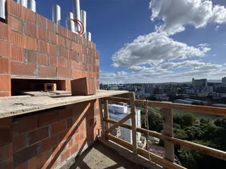 Vista da fachada de um prédio em construção com grade de madeira.
