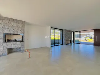Ambiente interno de uma sala de estar com lareira de pedra e portas de vidro.