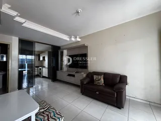 Sala de estar com sofá marrom e acesso à cozinha através de portas de vidro.