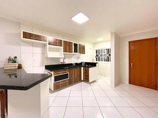Vista da cozinha com armários de madeira e bancadas escuras.