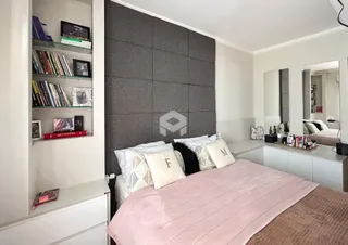 Quarto com cama e estante de livros em um apartamento.