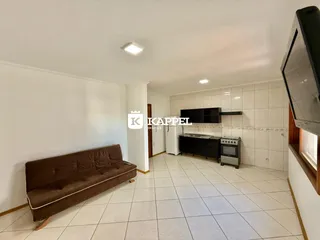 Sala de estar com sofá marrom e área de cozinha com piso de azulejo claro.