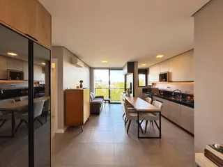 Ambiente moderno de sala de estar, jantar e cozinha com vista para a paisagem.