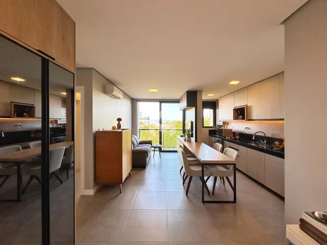Ambiente moderno de sala de estar, jantar e cozinha com vista para a paisagem.