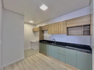 Cozinha moderna com armários de madeira clara e bancadas escuras.