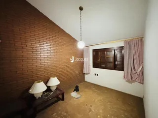 Interior de um cômodo com parede de tijolos aparentes e piso cru.