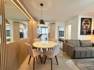 Uma sala de jantar moderna com mesa redonda e cadeiras claras.