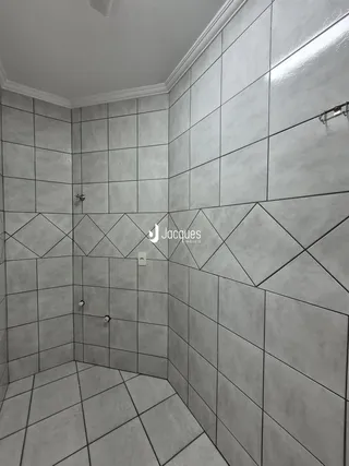 Interior de um banheiro com revestimento de azulejos cinzas.