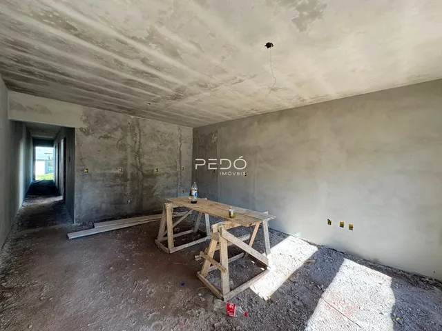 Vista interna de um ambiente em construção com paredes de concreto aparente.