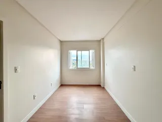 Sala de estar com piso de madeira e janela com vista para a paisagem.
