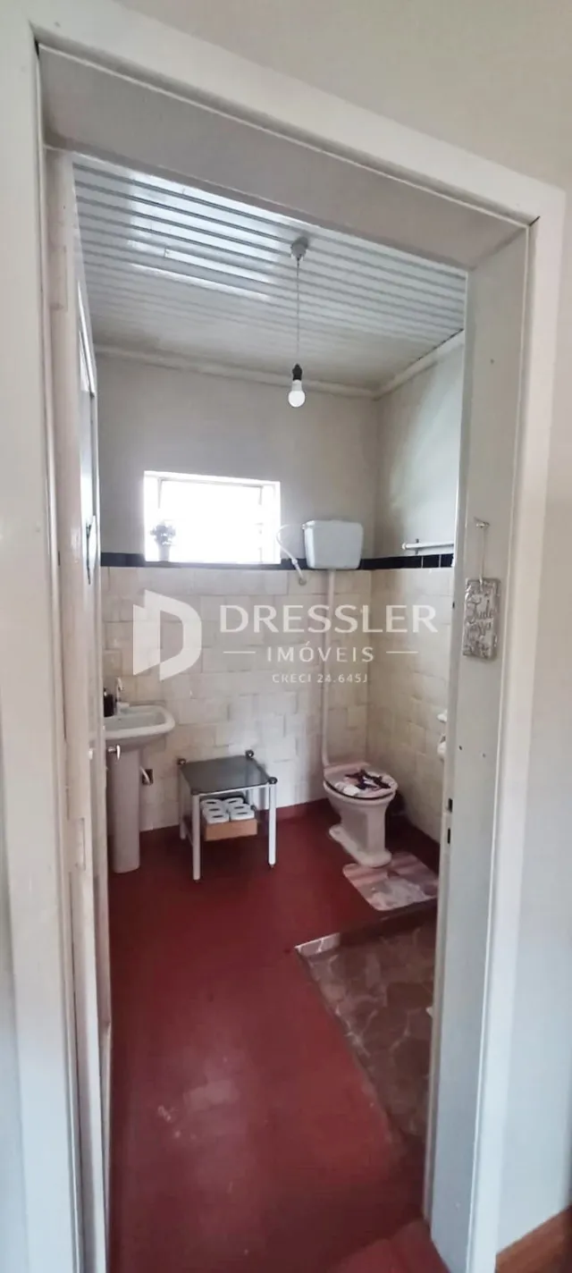 Banheiro com piso vermelho e azulejos brancos.