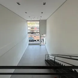 Vista de um corredor interno com paredes brancas e piso claro.