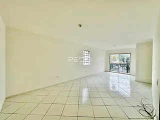 Interior de uma sala ampla com piso de cerâmica branca.