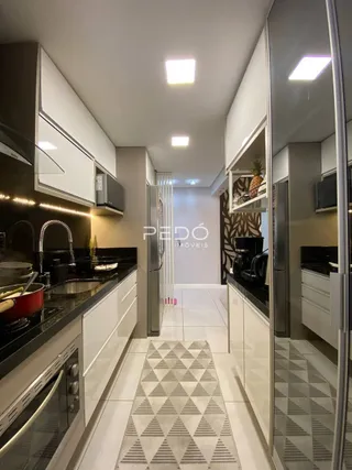 Vista do interior de uma cozinha moderna com armários brancos e piso de cerâmica.