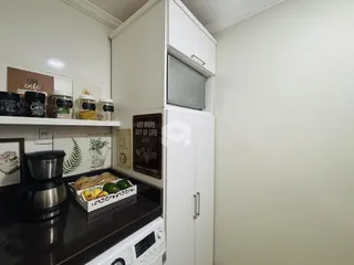 Cozinha com armários brancos e bancada escura.
