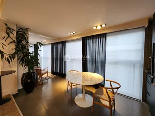 Sala de jantar com mesa redonda de mármore e grandes janelas.