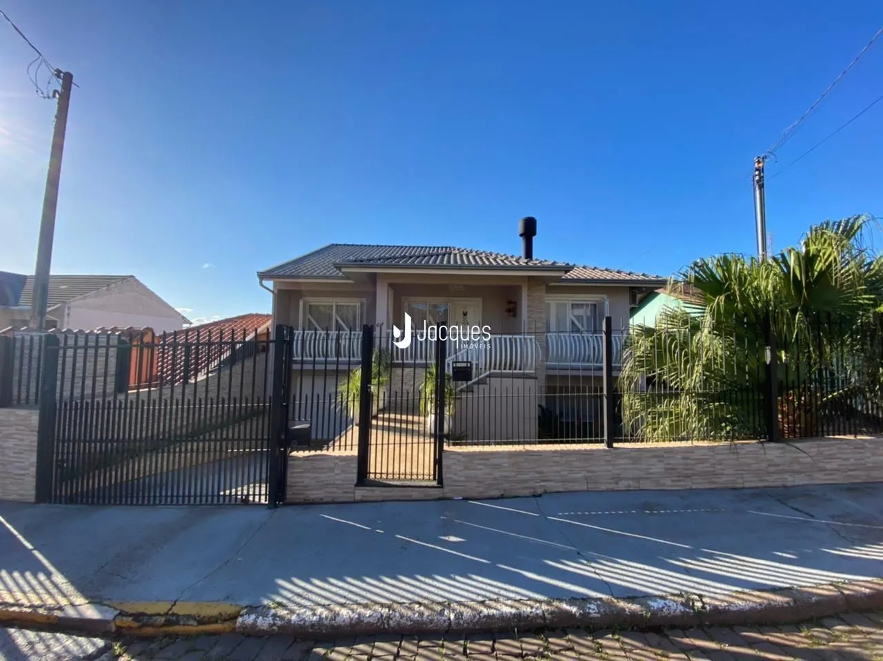 Fachada de uma casa em Lajeado, Brasil com cerca e portão de ferro.