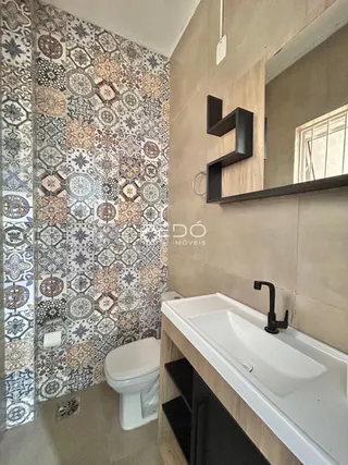 Foto de um banheiro com revestimento de parede estampado e louças sanitárias.