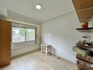 Vista interna de um cômodo com piso de madeira clara e janela.