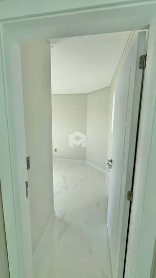 Corredor interno com piso de mármore branco e paredes brancas.