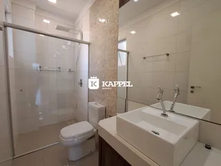 Banheiro moderno com box de vidro e pia branca.