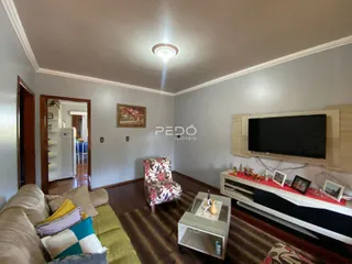 Sala de estar com sofá, poltrona e televisão em ambiente com piso de madeira.