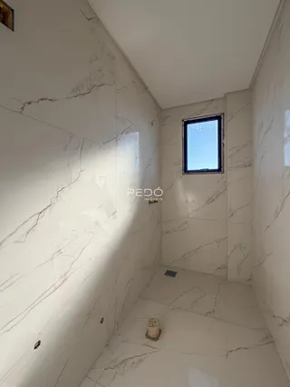 Corredor interno com paredes brancas e acabamento em mármore.