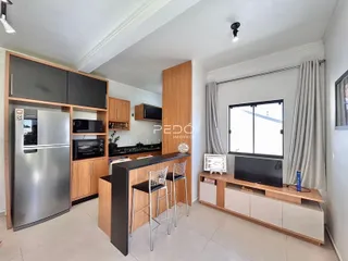 Sala de estar e cozinha moderna com armários de madeira e bancada.
