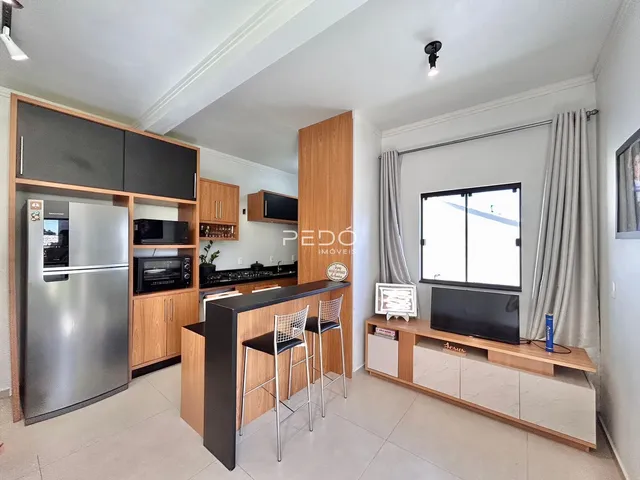Sala de estar e cozinha moderna com armários de madeira e bancada.
