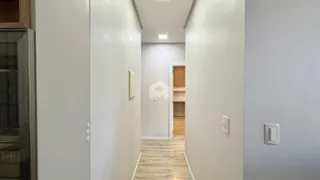 Corredor interno com piso de madeira clara em uma residência.