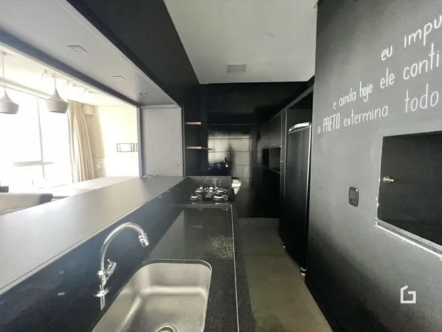 Vista da cozinha moderna com bancada escura e janela grande.