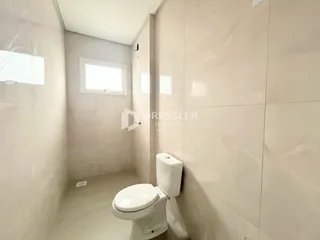 Interior de um banheiro com revestimento de cerâmica e vaso sanitário branco.