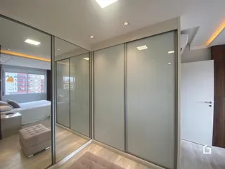Vista de um corredor interno com divisórias de vidro em um imóvel.