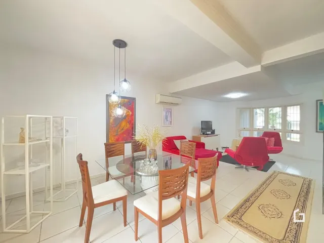 Sala de estar com mesa de jantar e sofá vermelho em um apartamento.
