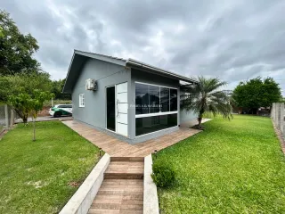 Fachada de uma casa moderna com deck de madeira e gramado verde.