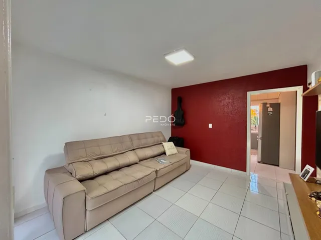 Sala de estar com sofá bege e parede vermelha em um imóvel no Brasil.