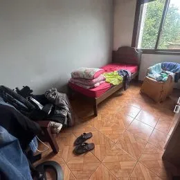 Quarto com piso de cerâmica e itens de cama visíveis.