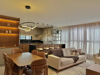 Sala de jantar e cozinha com sofá e luz natural.