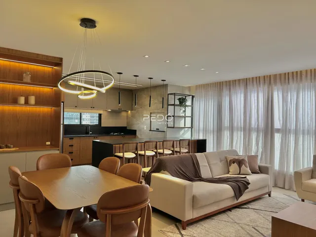 Sala de jantar e cozinha com sofá e luz natural.