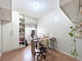Ambiente interno de uma sala com piso de madeira clara e armários brancos.