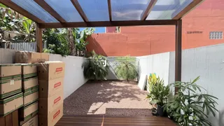 Vista externa de um jardim com paredes de cor terracota e um deck de madeira.