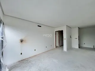 Interior de um espaço com paredes brancas e piso de concreto aparente.