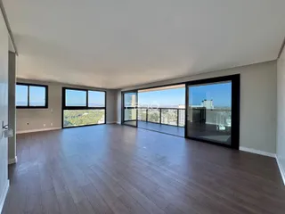 Sala de estar ampla com piso de madeira e vista panorâmica da cidade.