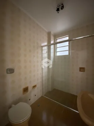 Foto interna de um banheiro com revestimento de parede e box de vidro.