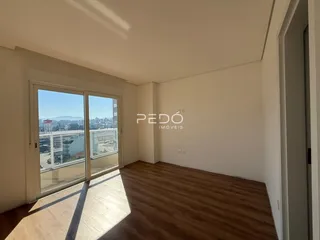 Sala de estar com piso de madeira e portas de vidro que dão para a vista.