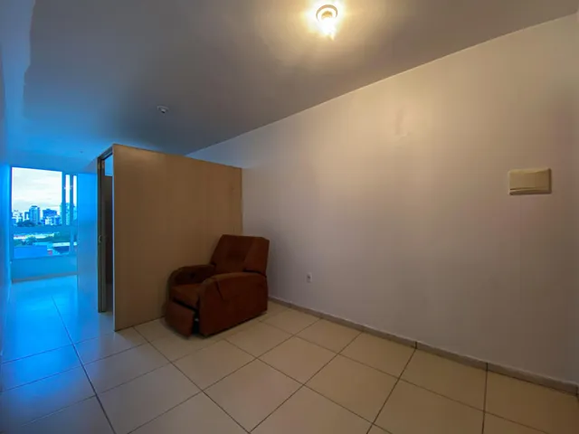 Ambiente interno com piso de cerâmica e uma poltrona em uma sala de estar.